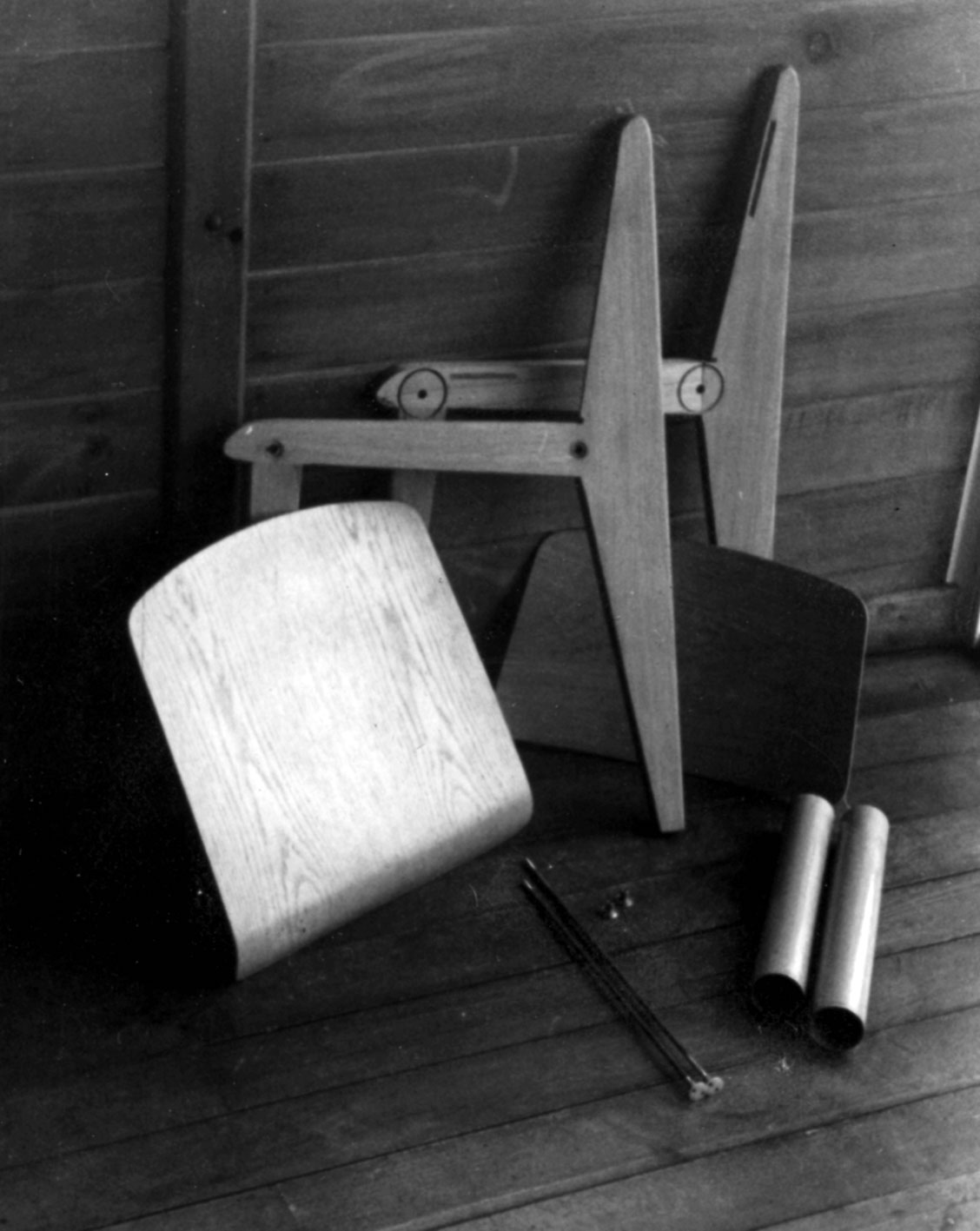 Chaise bois démontable CB 22. Démonstration du montage par André Le Stang, collaborateur des Ateliers Jean Prouvé, dans le bureau de Jean Prouvé à Maxéville, c. 1949.