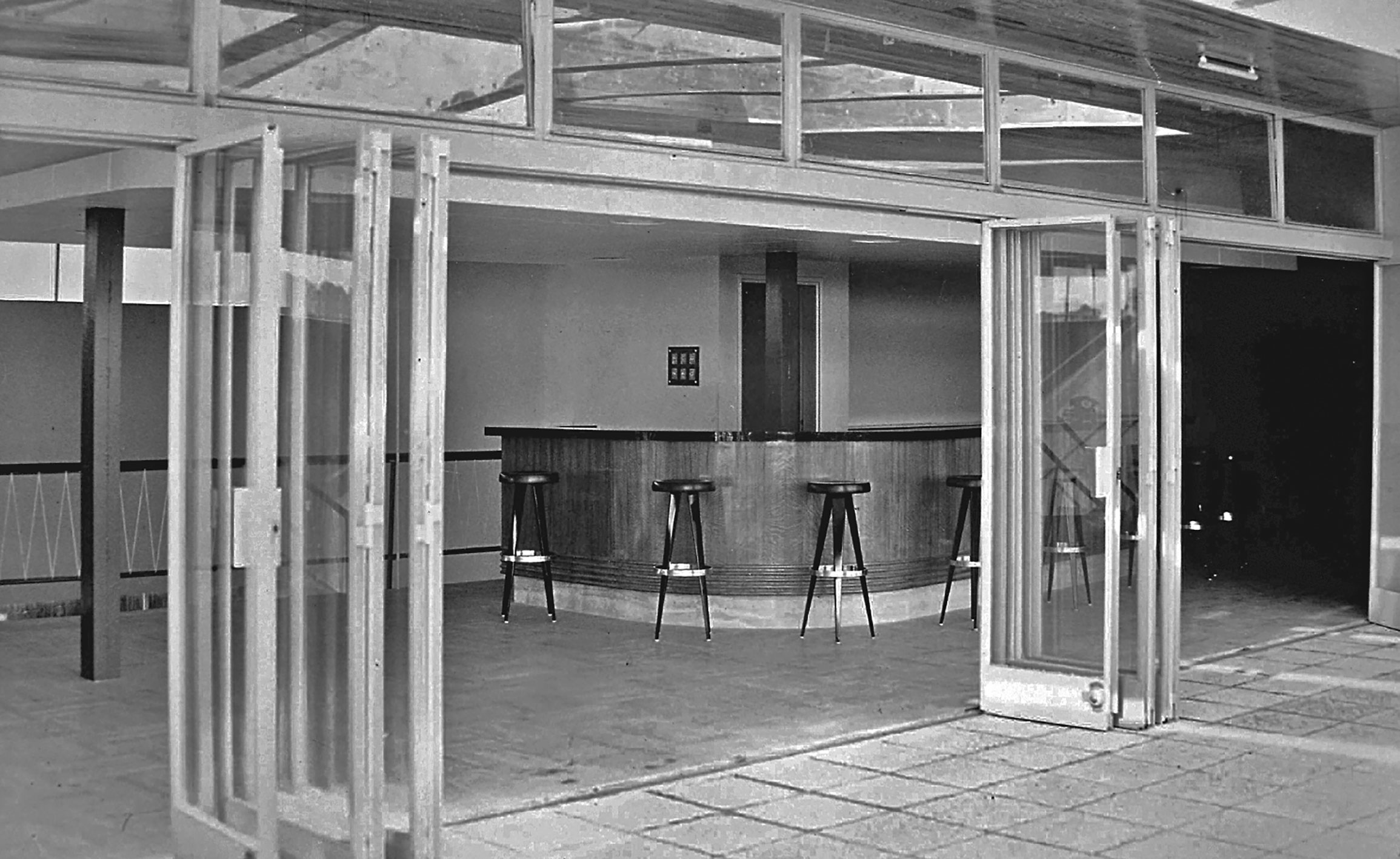 Commissariat à l’énergie atomique, centre de Marcoule, Bagnols-sur-Cèze. L’espace bar du réfectoire équipé de tabourets hauts, c. 1955.