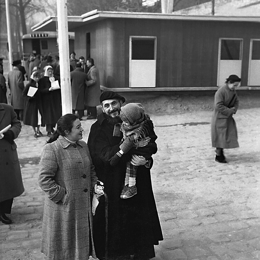 L’abbé Pierre en compagnie de la famille à laquelle la maison Les Jours Meilleurs est destinée, quai Alexandre-III, Paris, février 1956.