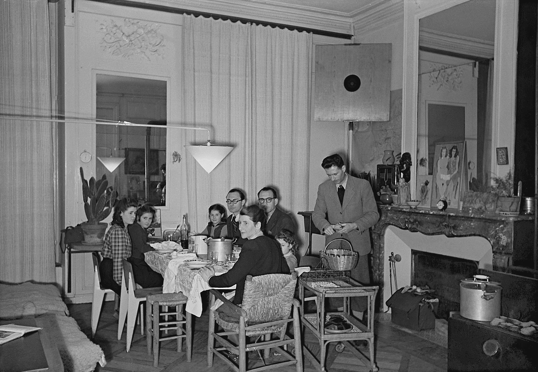 The Prouvé family’s apartment, Place de la Carrière, Nancy. The dining area with a large swing-jib lamp. Straw armchair and stool by Charlotte Perriand. Visit by the Lods family and architect B. Bijvoet, ca. 1945.