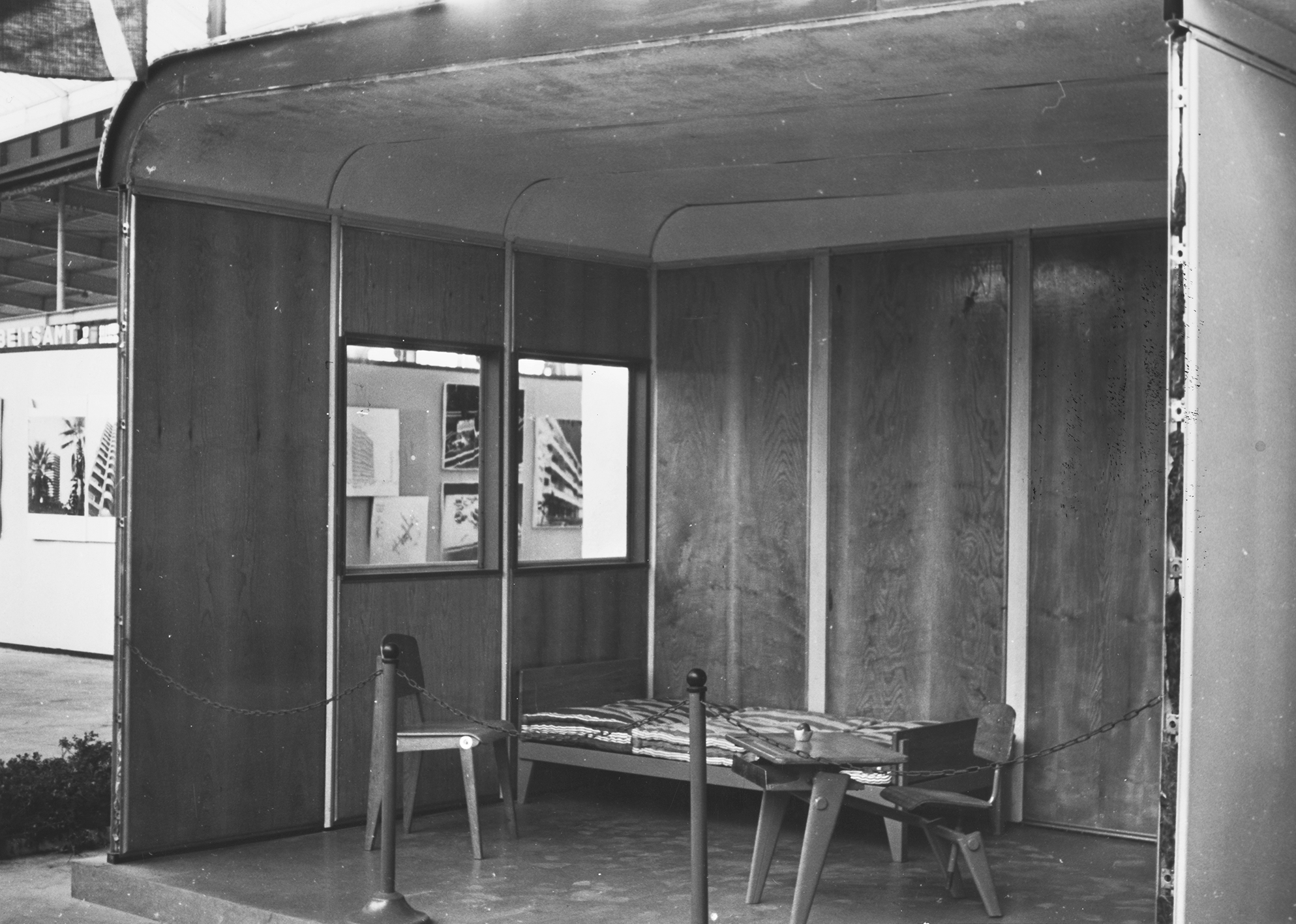 Salon des Arts ménagers, exposition de l’Habitation, Paris, 1953. Stand des Ateliers Jean Prouvé. Maison Coque équipée d’un lit type Flavigny, une chaise CB 22, et un pupitre monoplace.