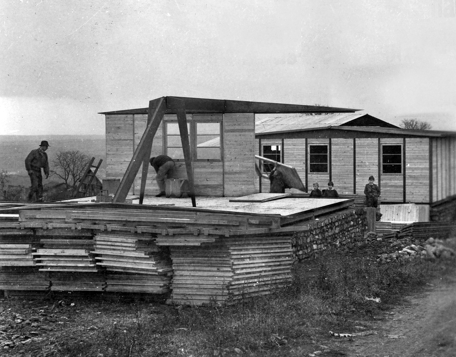 Montage des maisons 8 m x 8 m. Vue partielle du lotissement réalisé avec des bâtiments à portiques des Ateliers Jean Prouvé, Bezaumont, automne 1945.